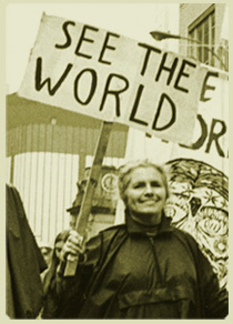 Photo of Grace Paley at a New York City demonstration, carrying a sign that says "See the World".